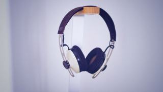 Casque supra-auriculaire à arceau de cuir suspendu contre un mur clair